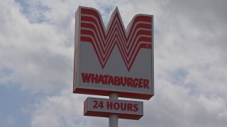 Letrero grande de Whataburger con el característico logo en forma de 'W' ubicado frente al restaurante de comida rápida.