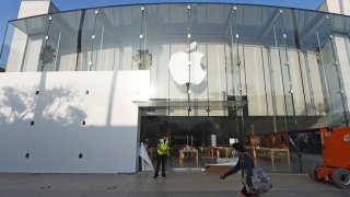 Una mujer usa mascarilla mientras pasa frente a una tienda Apple en Santa Mónica, California.